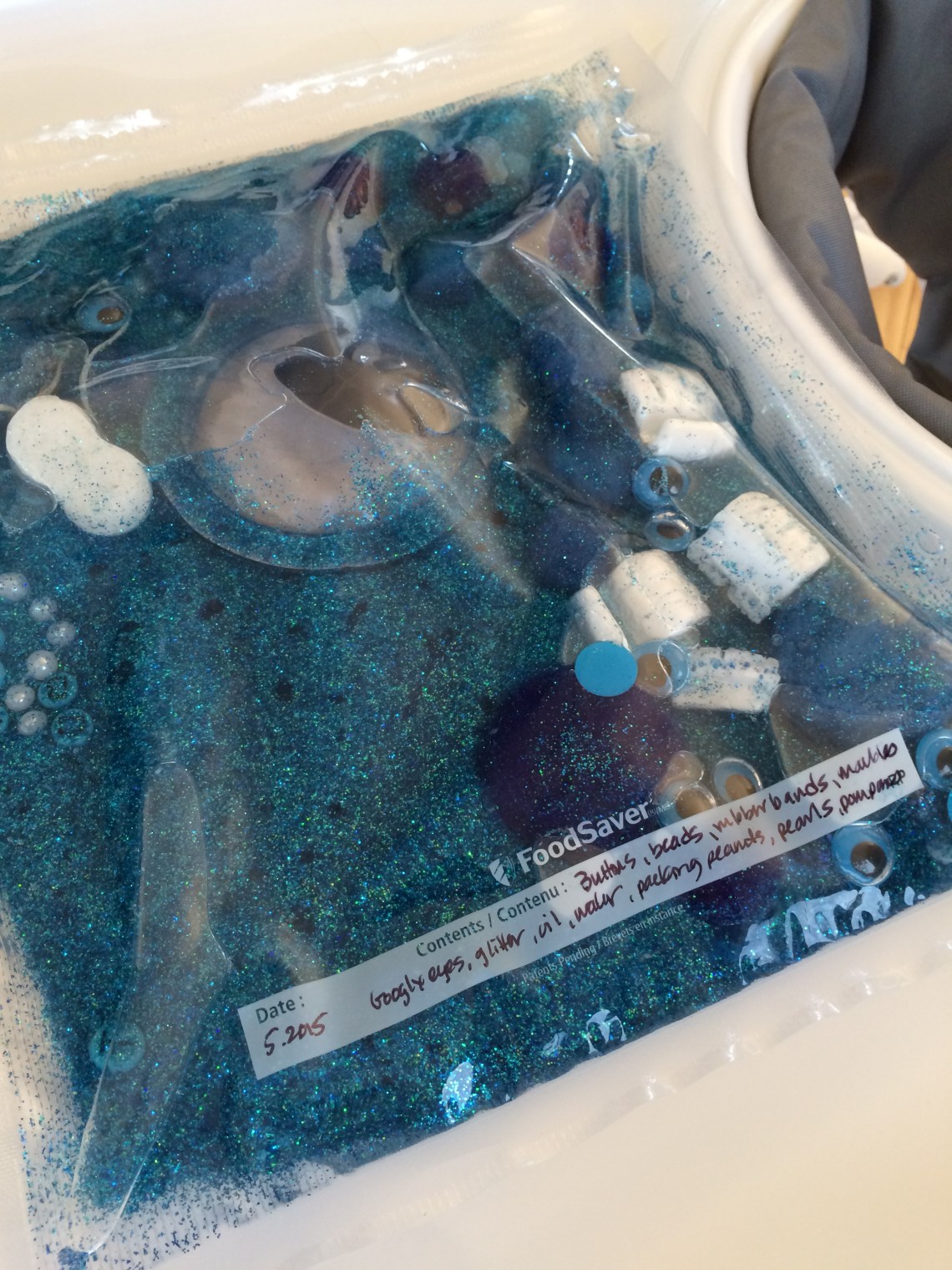 contents blue baby oil glitter sensory mat pompoms rubber bands beads foodsaver sealed giant google eyes